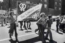 LGBTQ+ march highlighting two people carring a flag labeled Gay Liberation front.